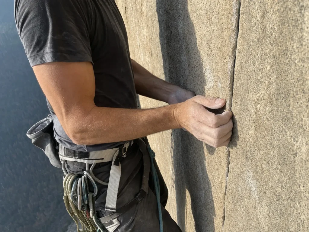 Climber crimping a thin seam on the blank granite of El Capitan's Dawn Wall tier
