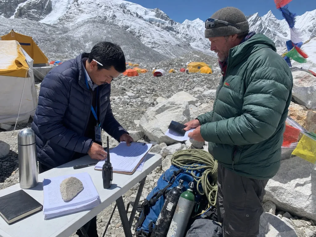 Liaison officer checking climbing permits and paperwork at an Everest base camp checkpoint