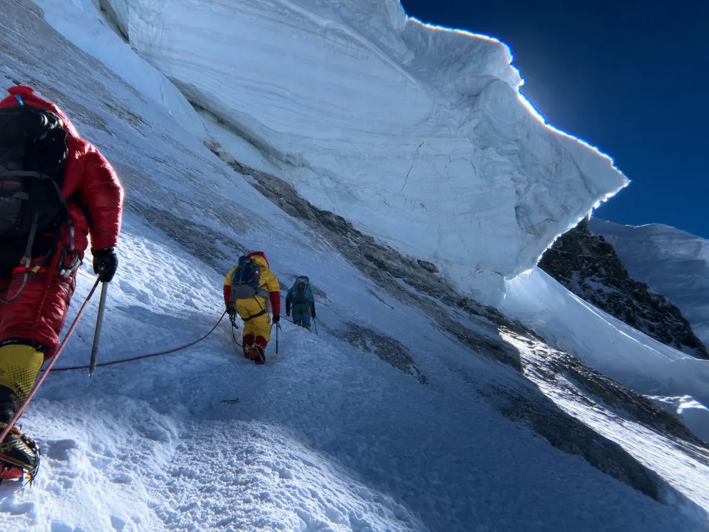 Climbers traversing beneath the hanging serac at K2's Bottleneck