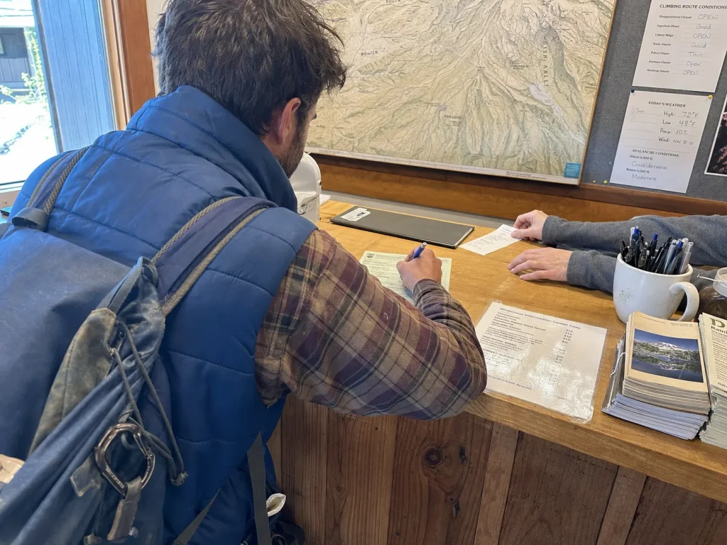 Climber filling out a Mount Rainier climbing registration at a ranger station counter