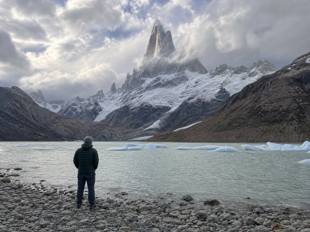 Lone trekker at Laguna Torre dwarfed by Cerro Torre, a humbling view of an elite objective