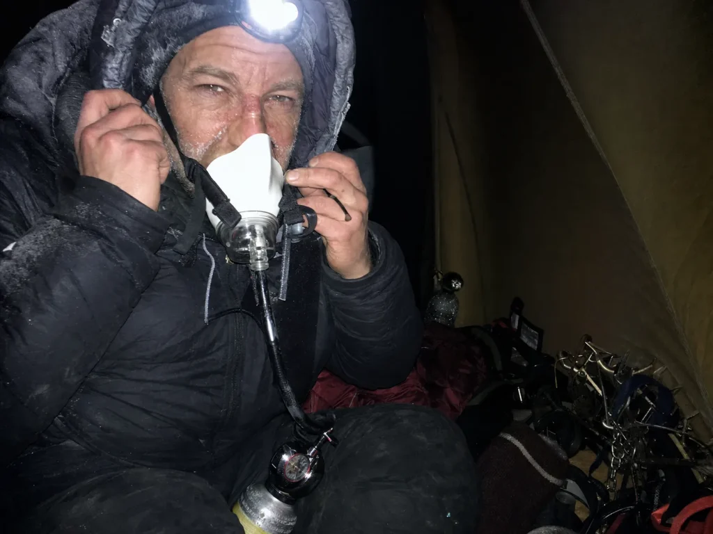 Climber fitting an oxygen mask by headlamp before a pre-dawn Everest summit push