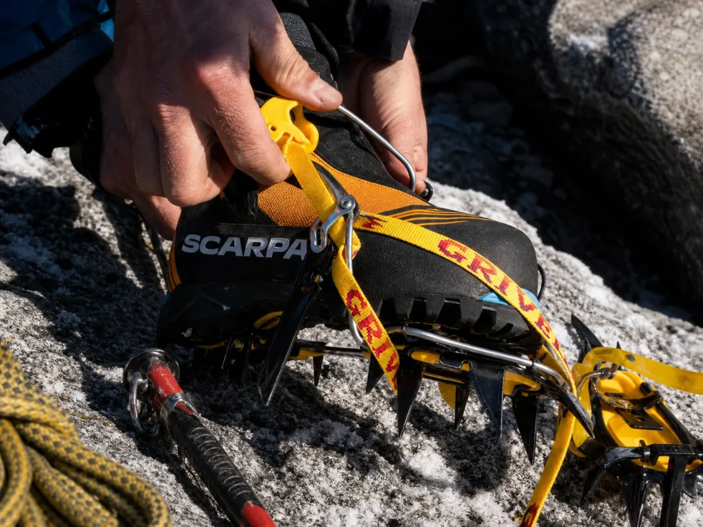 Steel hybrid crampons being fitted to a double mountaineering boot for Fitz Roy's mixed terrain