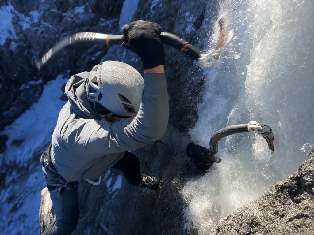Climber swinging an ice tool on a steep mixed rock-and-ice pitch