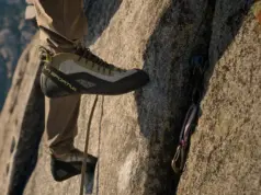 Best Climbing Shoes for Trad Without the Ankle Pain Trad climber's foot in a stiff high-top climbing shoe edging on a granite ledge above placed cams