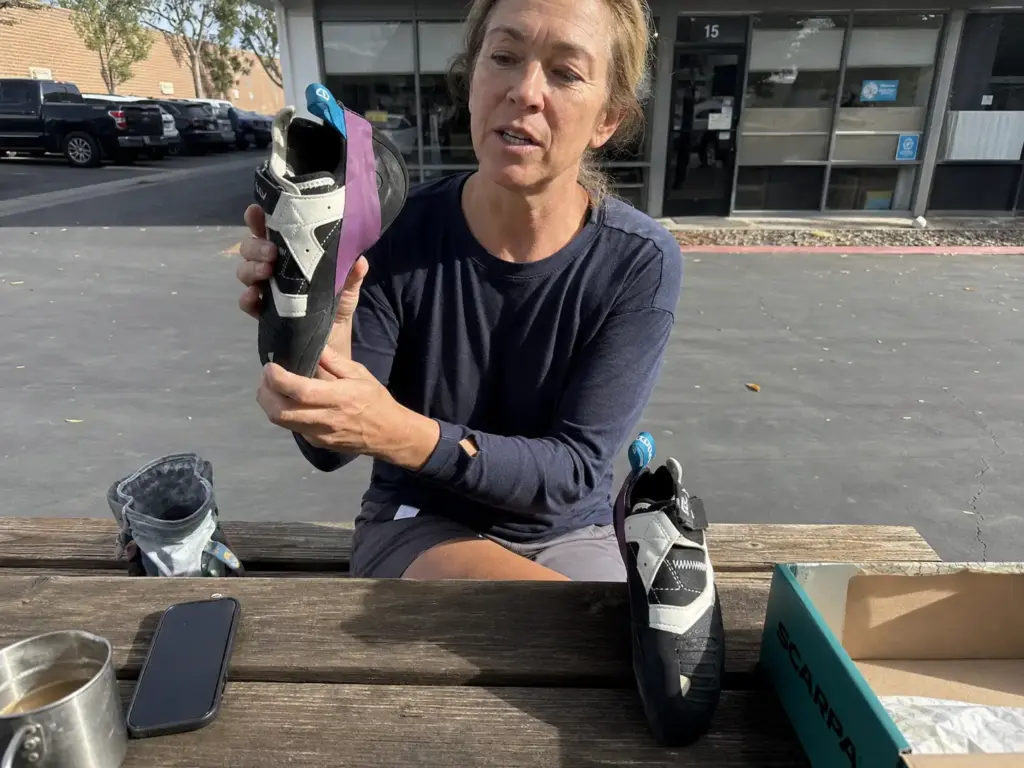 Climber holding a low-volume LV climbing shoe next to a standard-volume pair to compare lasts