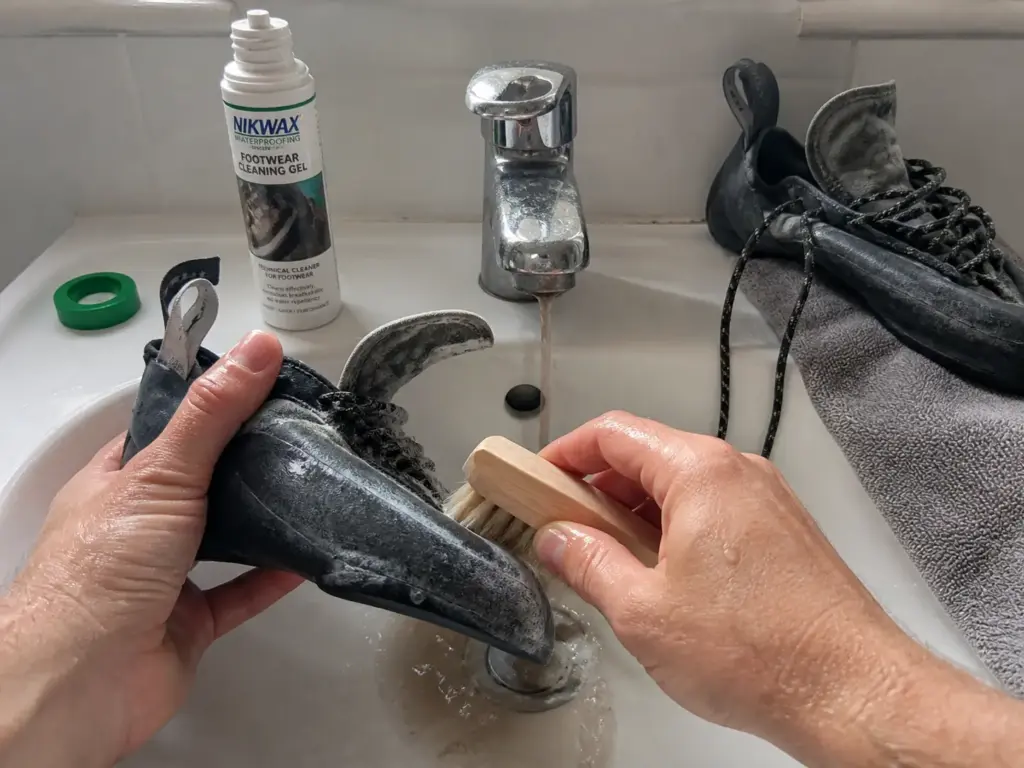 Hand washing a climbing shoe with a soft brush and cleaning gel until water runs clear
