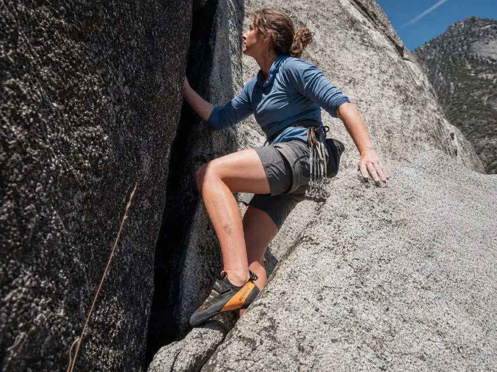 Climber weighting a small granite edge with the big toe of a stiff climbing shoe on a long route
