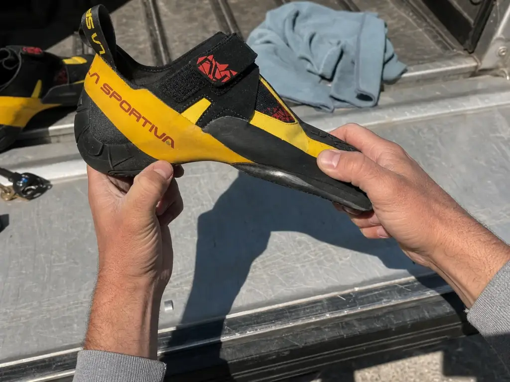 Hands flexing the upper of a climbing shoe to compare leather and synthetic stretch