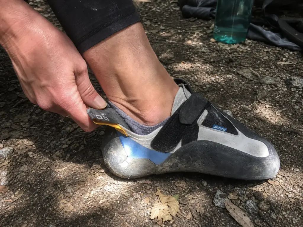 Climber pinching the heel of an oversized climbing shoe showing dead space from sizing up