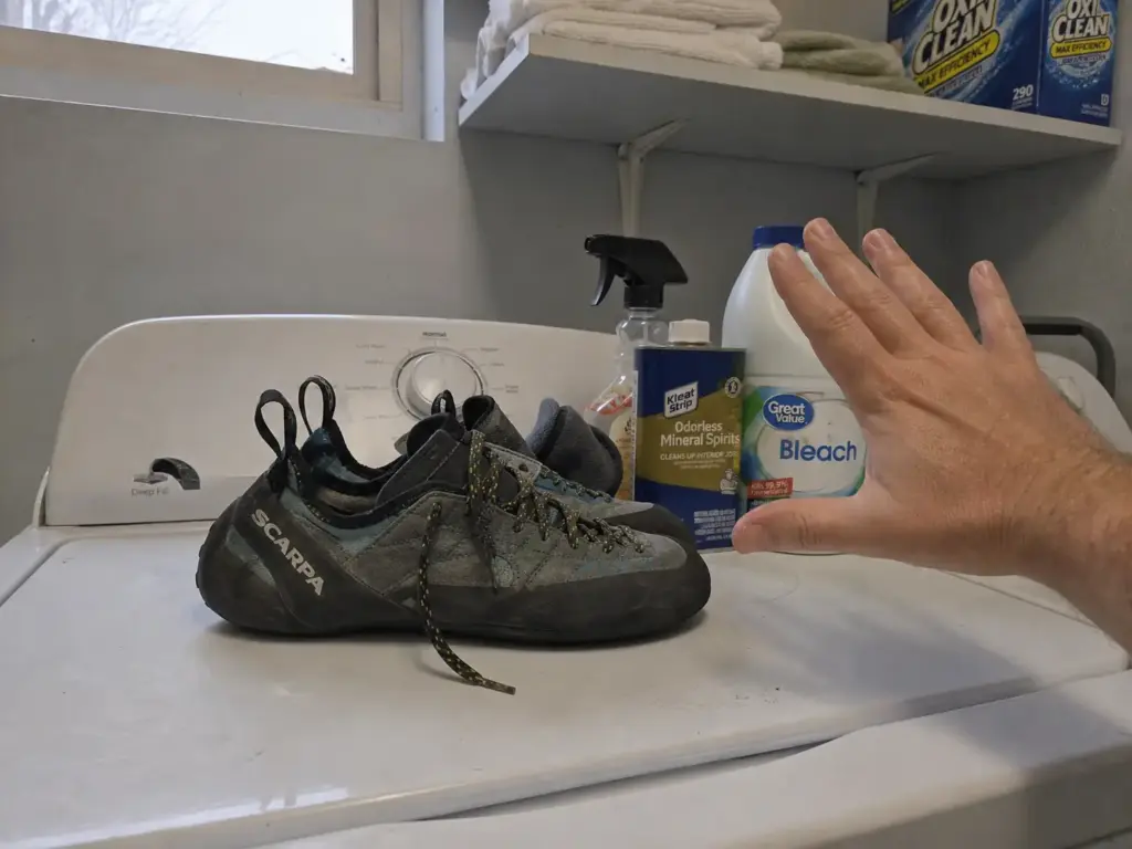Climbing shoes set on a washing machine beside bleach and solvents that damage them